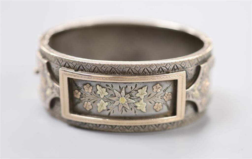 A late 19th century white and two colour yellow metal overlaid hinged bangle, gross 35.4 grams,